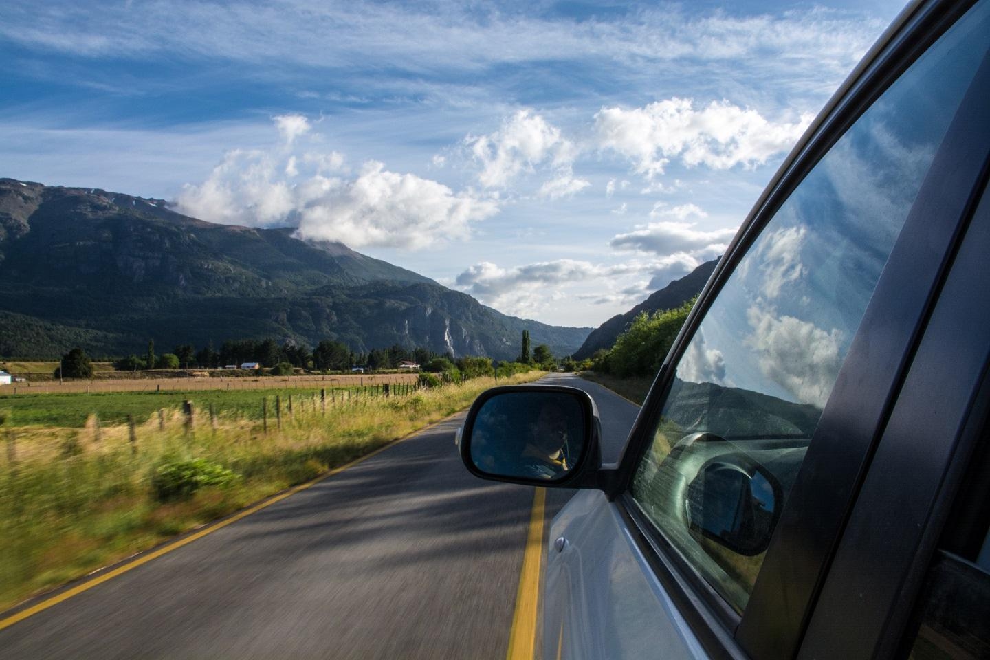 car_driving_down_a_road_with_moountains_in_the_background