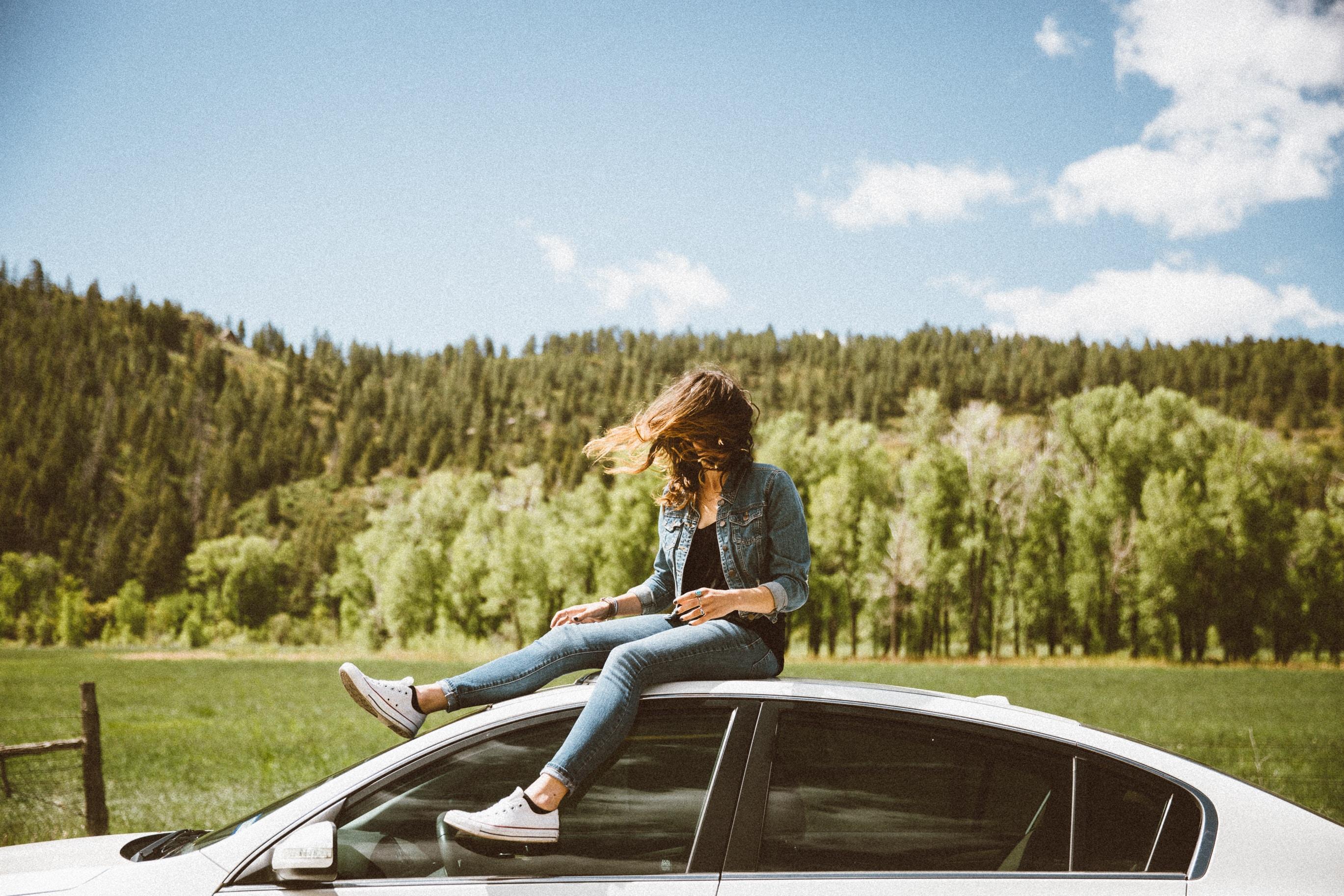 woman_sitting_on_the_roof_of_her_car_in_a_field