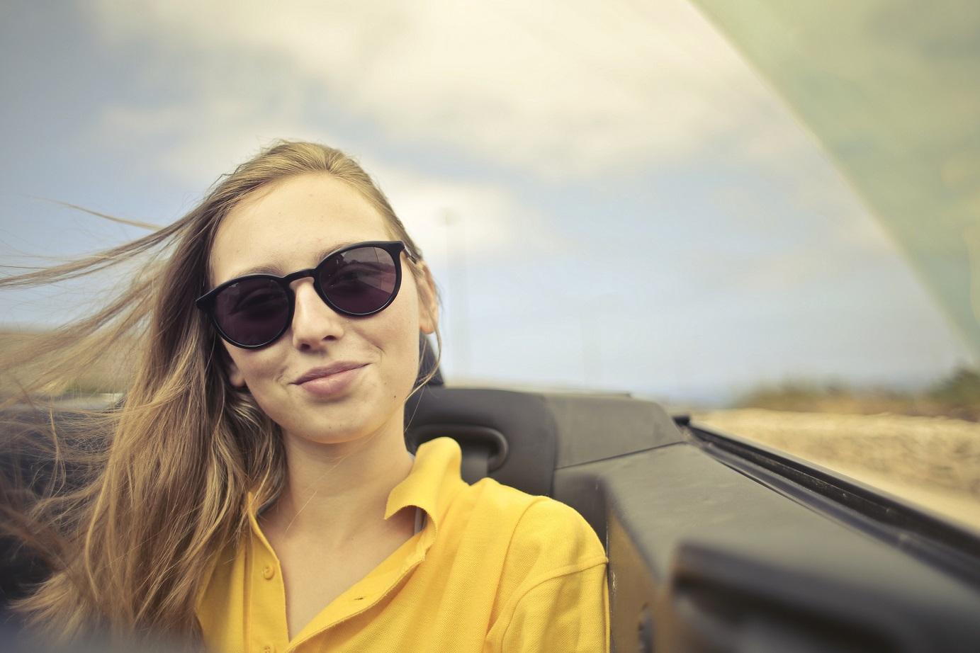 woman_in_sunglassses_and_a_yellow_shirt_sitting_in_the_passener_seat_of_a_car