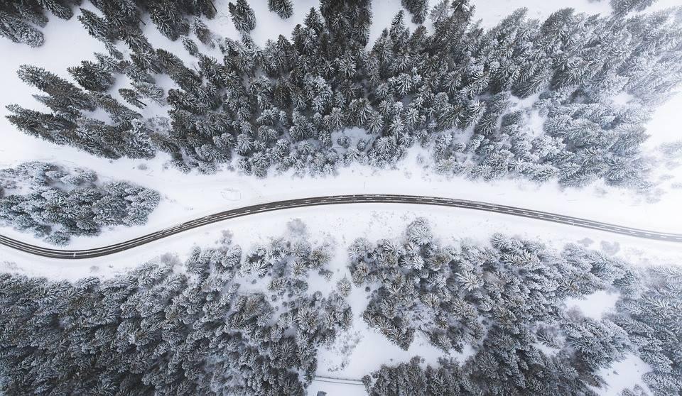 birds_eye_view_of_a_road_through_a_snowy_forest