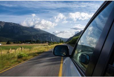 car_driving_down_a_road_with_moountains_in_the_background