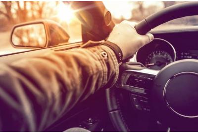 a_man_in_a_long_sleeved_jacket_with_his_left_hand_on_the_steering_wheel