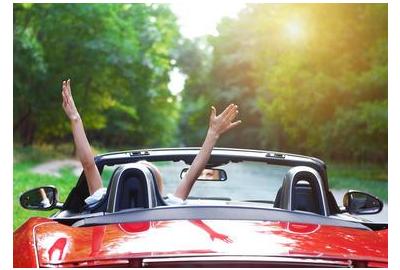 a_persons_hands_in_the_air_in_exclamation_in_a_convertable