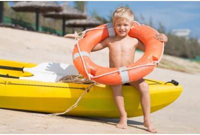 child_holding_a_lifering_on_abeach_next_to_a_kiak