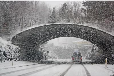 car_driving_under_a_bridge_in_snowy_weather