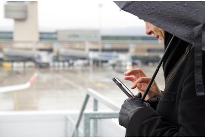 a_woman_under_an_umbrella_texting_outside_of_a_station