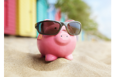 pink savings piggy bank in sunglasses sitting on the beach