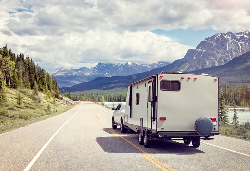 electric car towing a caravan trailer on mountain view road