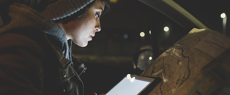 young woman in car looking at map at night